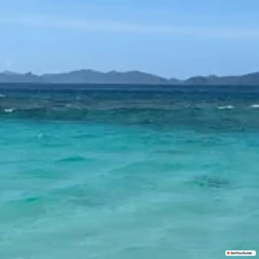 Hidden beach and clear water beneath cliffs in Bacuit Bay