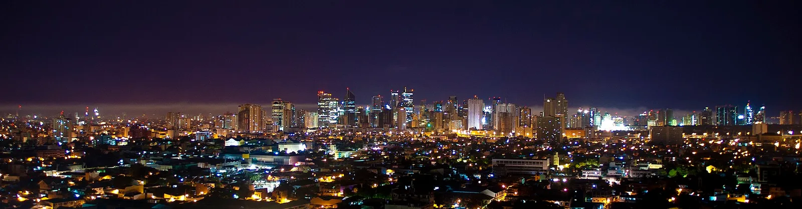 Rooftop bar in Makati with city lights and the BGC skyline visible across the Pasig River at night